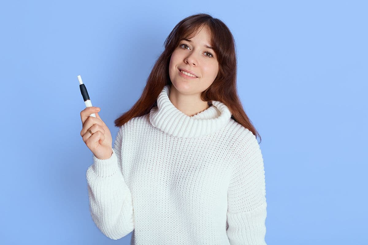 young woman blue lady with good mood looks camera holds e ciggy her hand wearing casual attire has dark hair